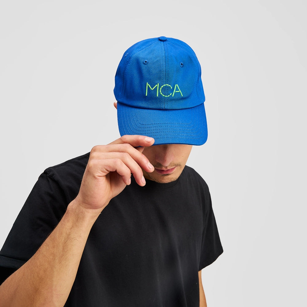 Person wearing a blue cap with 'MCA' logo on a light gray background