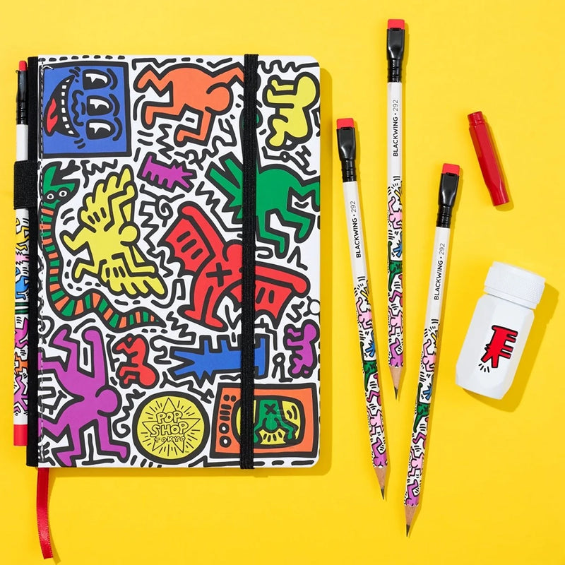 Colorful notebook with art-style design, pencils, and a sharpener on a yellow background